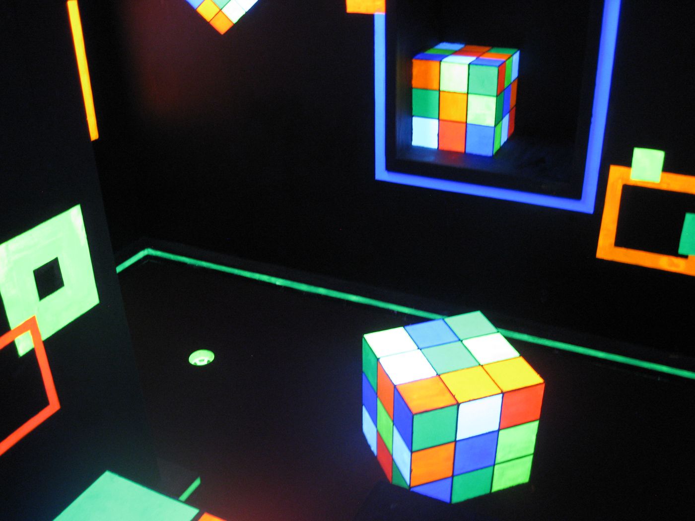 Neon Rubik's cube themed mini golf hole under black light at Glow Games Twin Falls